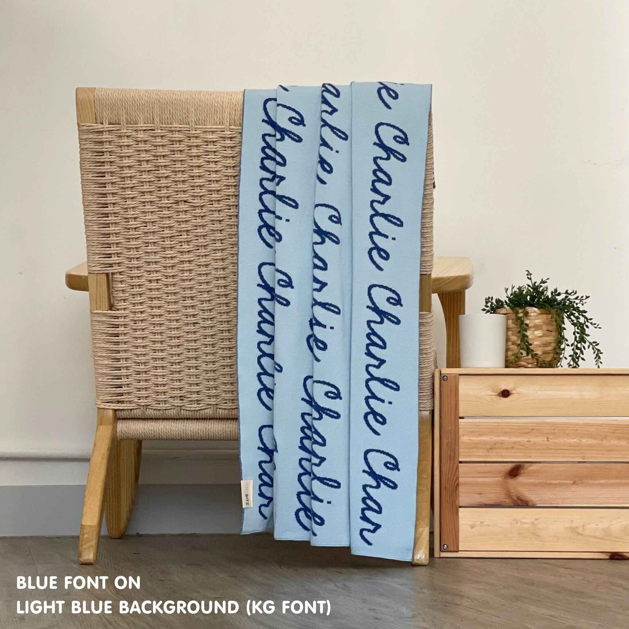 Personalised pet blanket in light blue and blue knitted cotton, custom dog blanket by TinyBitz, styled on modern wooden dog bed.