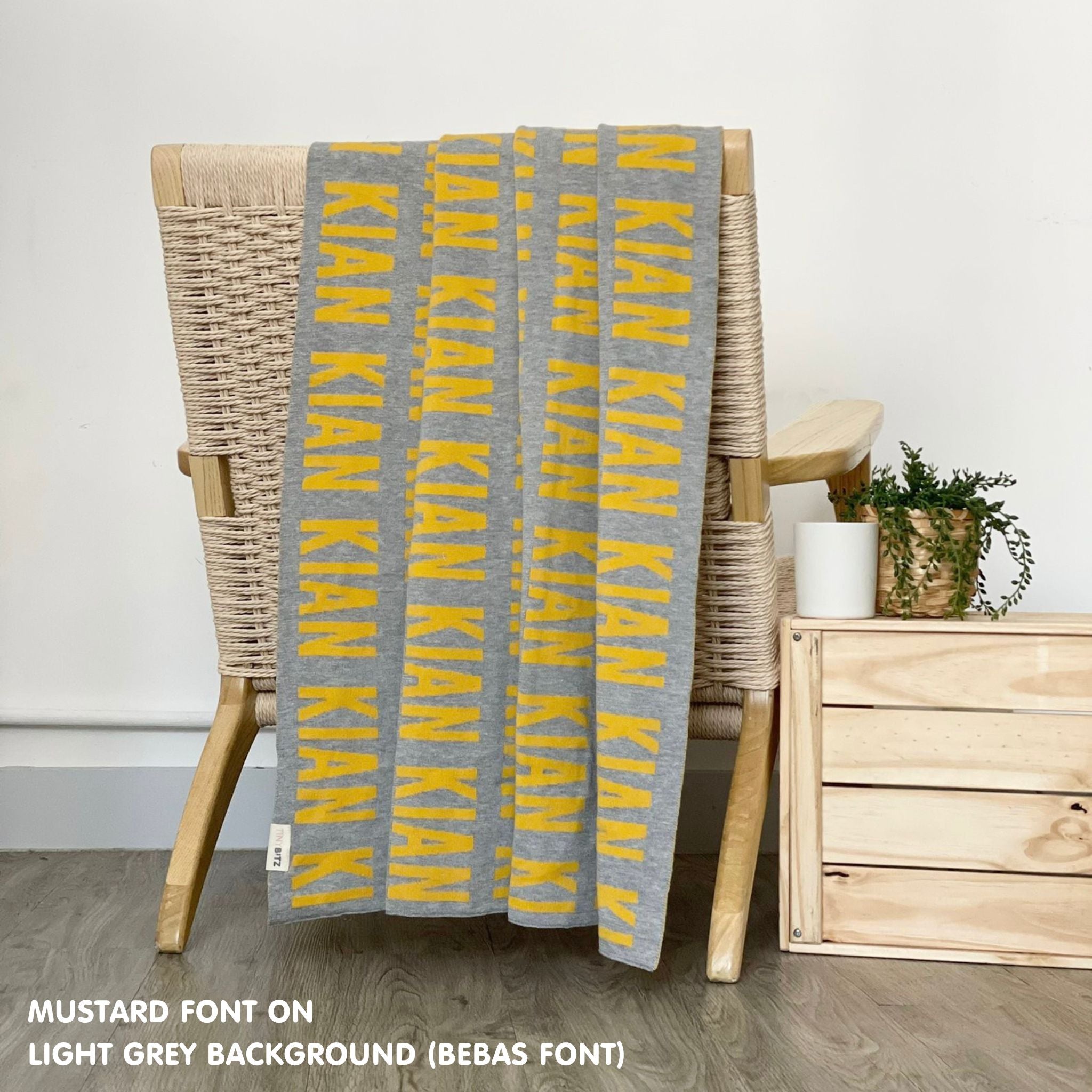 Personalised pet blanket in light grey and mustard knitted cotton, custom dog blanket by TinyBitz, styled on modern wooden dog bed.