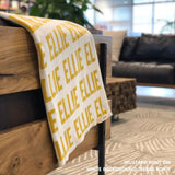 Personalised pet blanket in white and mustard knitted cotton, custom dog blanket by TinyBitz, styled on modern wooden dog bed.