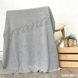 Knitted baby blanket in light grey background, customised with baby's name, made by TinyBitz.