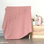 TinyBitz personalized knitted blanket in dusty pink background, customized with baby's name and made from 100% cotton.