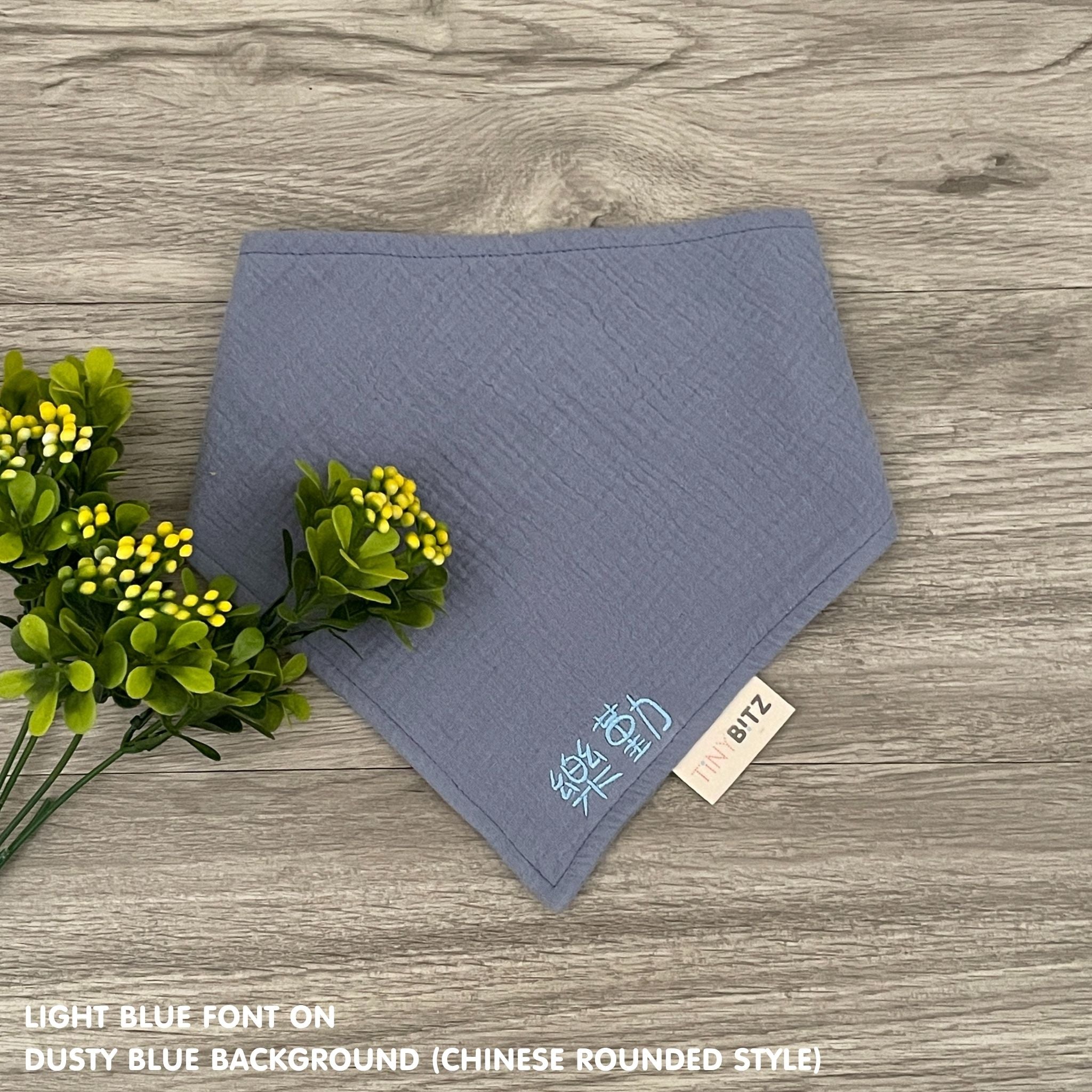 Personalized dusty blue organic muslin bib with custom name embroidery, perfect for baby gifts and keepsake accessories.