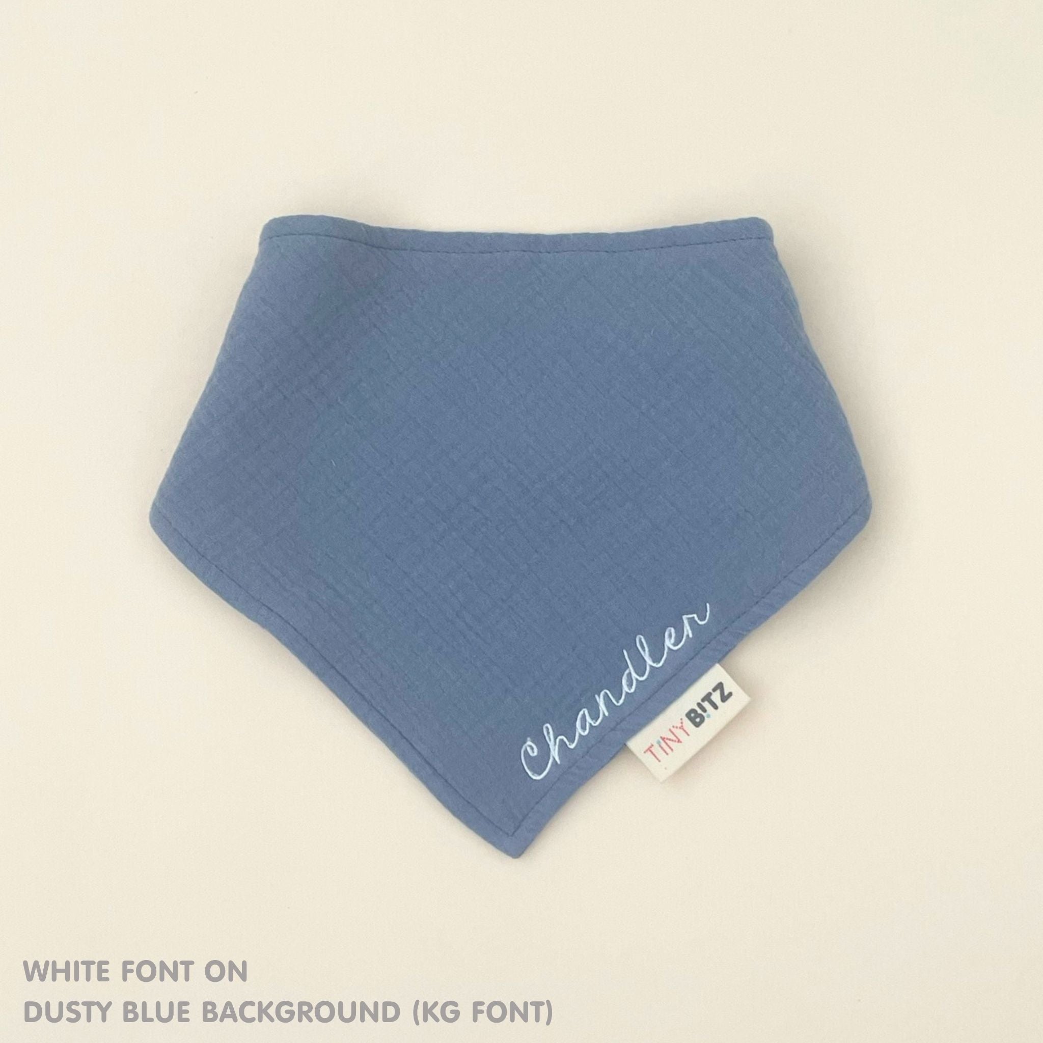 Custom baby bib in dusty blue with embroidered name, personalised baby gift made from breathable muslin by TinyBitz.