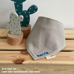 Personalized light grey organic muslin bib with custom name embroidery, perfect for baby gifts and keepsake accessories.