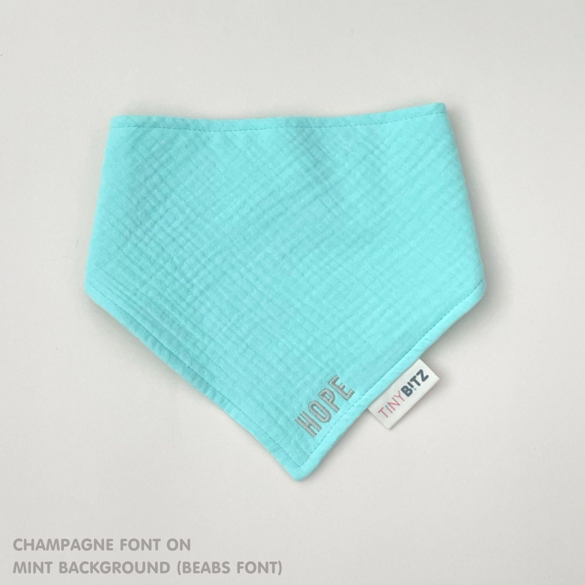 Custom baby bib in mint with embroidered name, personalised baby gift made from breathable muslin by TinyBitz.