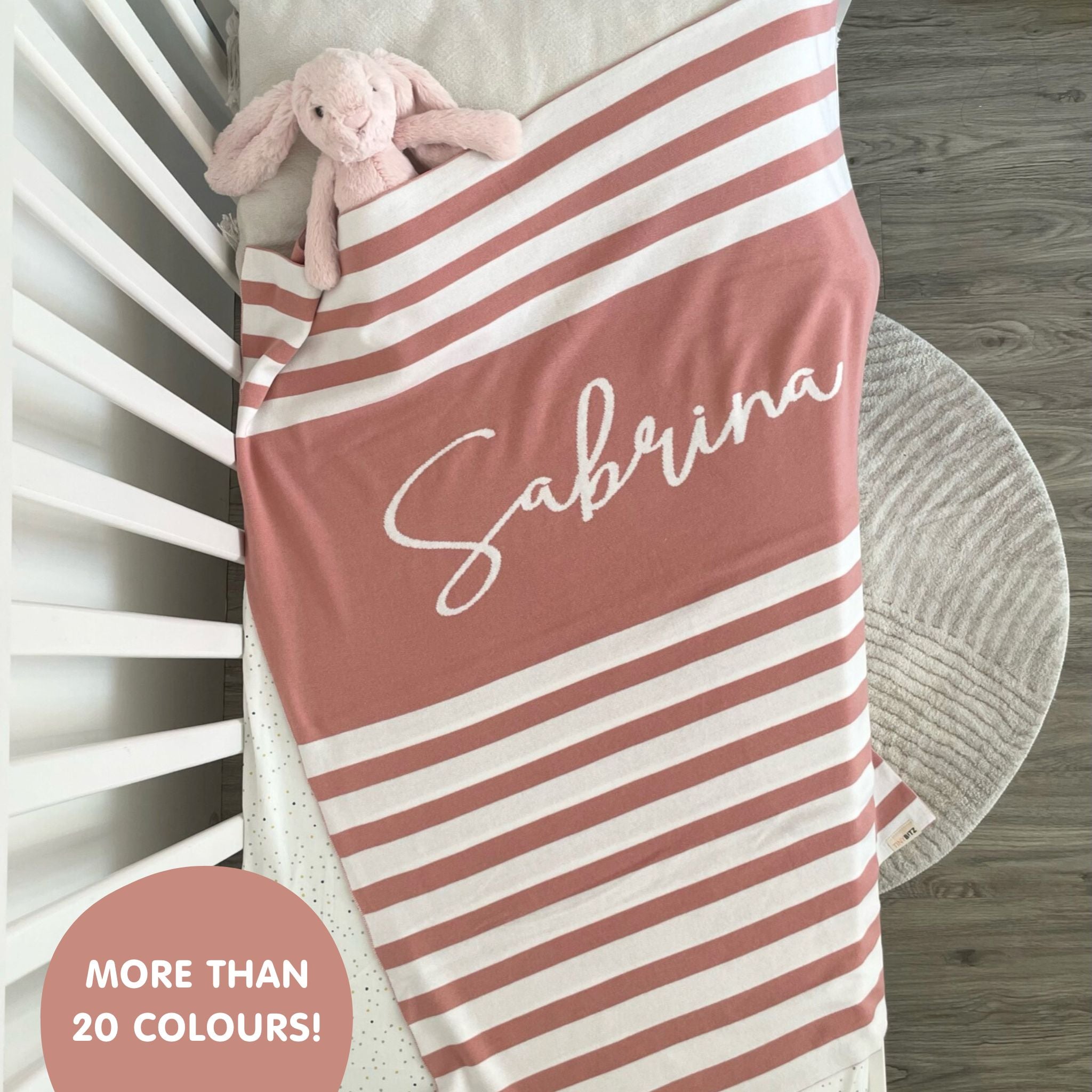 TinyBitz knitted name blanket in dusty pink and white with a stripes pattern, a lovely touch to decorate your baby's room!