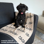Personalised pet blanket in oatmeal and charcoal knitted cotton, custom dog blanket by TinyBitz, styled on modern wooden dog bed.