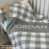 Knitted baby blanket in light grey and white with a check pattern, customised with baby's name, made by TinyBitz.