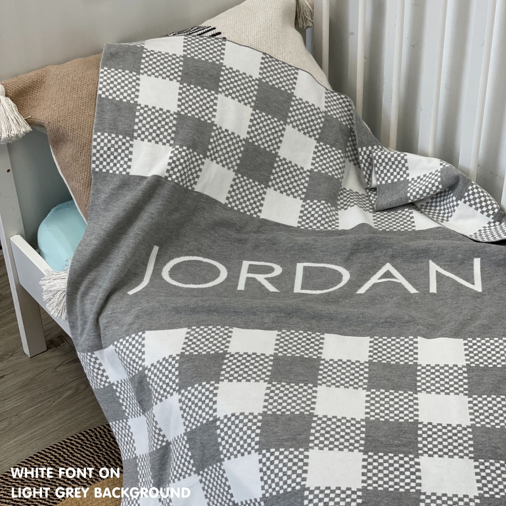 Knitted baby blanket in light grey and white with a check pattern, customised with baby's name, made by TinyBitz.