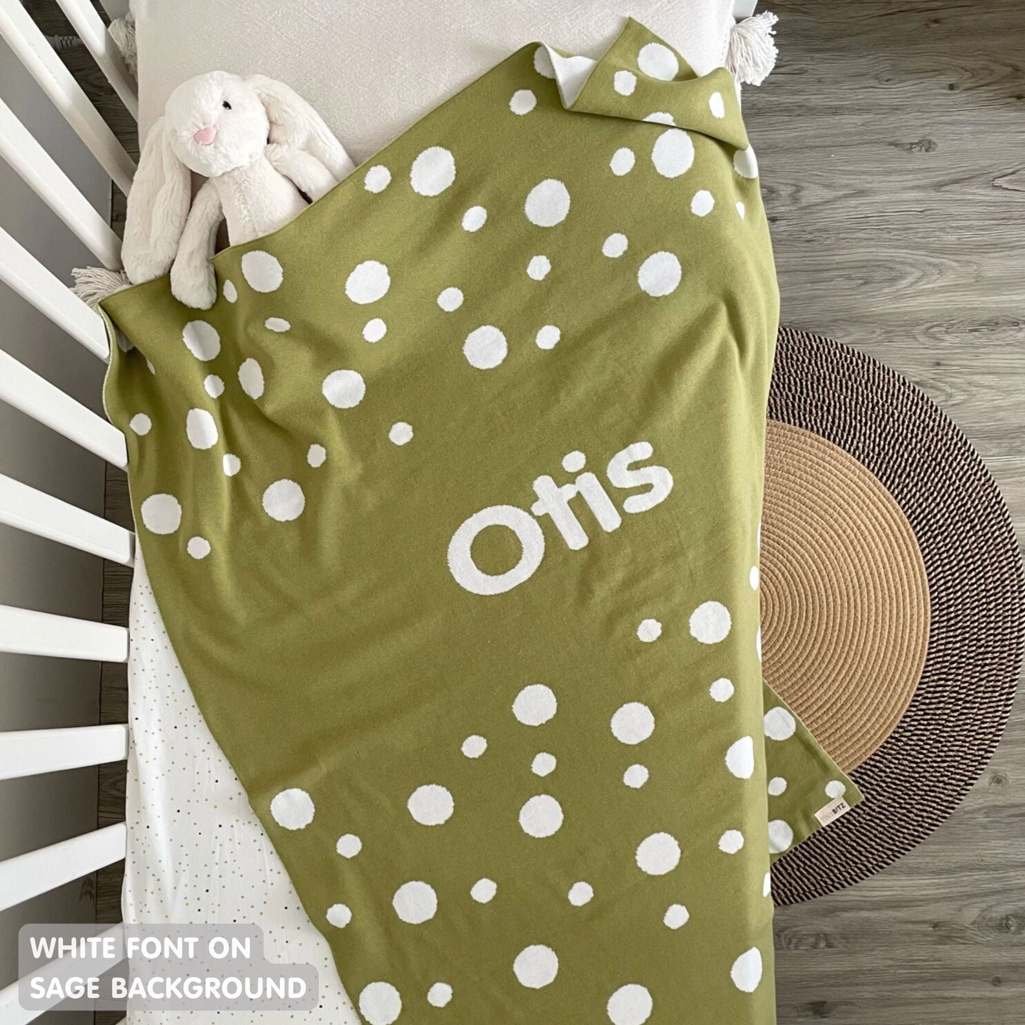 Cotton baby blanket with baby's name, knitted in sage and white with a dot pattern, made by TinyBitz.