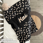 TinyBitz personalized name blanket in charcoal and oatmeal with a confetti pattern, perfect gift for newborn babies and kids.