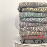 Knitted baby blanket in light grey background, customised with baby's name, made by TinyBitz.